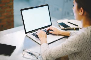 Person typing landing page copy on a laptop for a digital marketing campaign