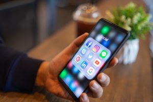 Close-up of a person holding a smartphone showing popular social media apps like Facebook, Instagram, Twitter, LinkedIn, and YouTube—ideal visual for digital marketing, social media strategy, or online branding content.