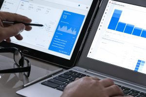 Businessman analyzing digital marketing data on tablet in modern office with city view, symbolizing strategic budget planning and competitor bidding decisions.